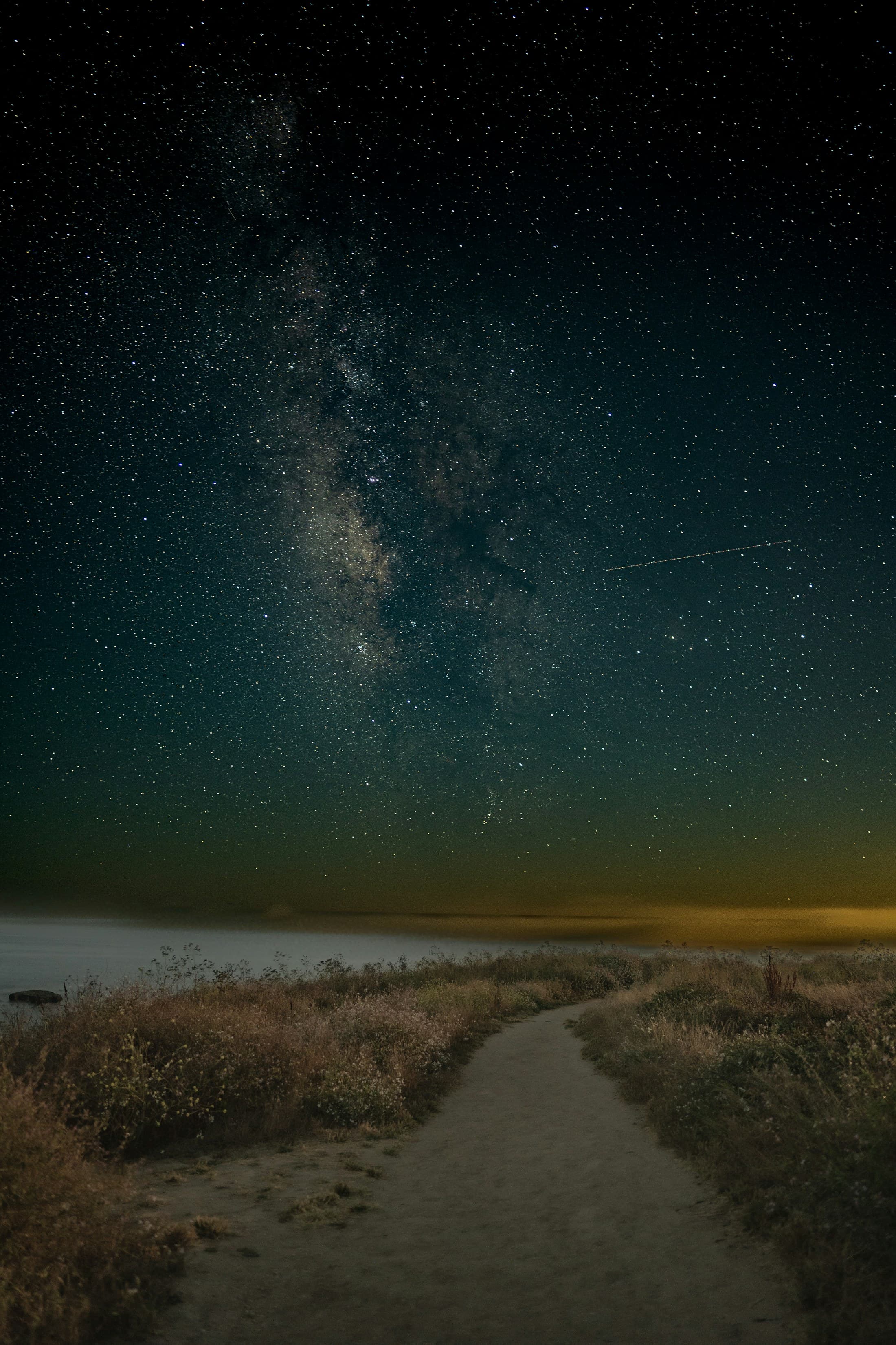 Placeholder photograph of a coastal path beneath the Milky Way, not a photograph of Jazmin